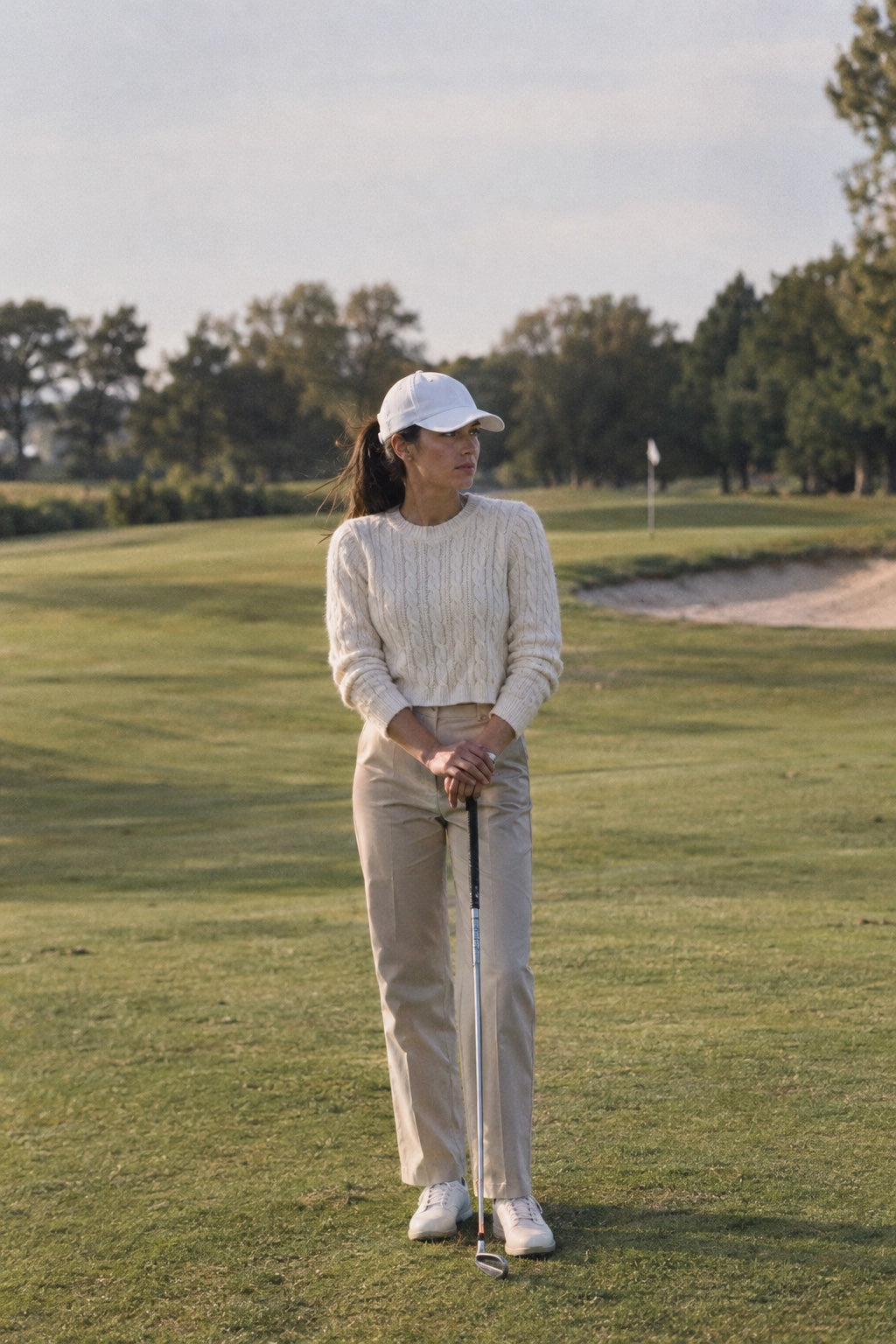 Golfeuse en pull torsadé crème et pantalon beige sur le fairway